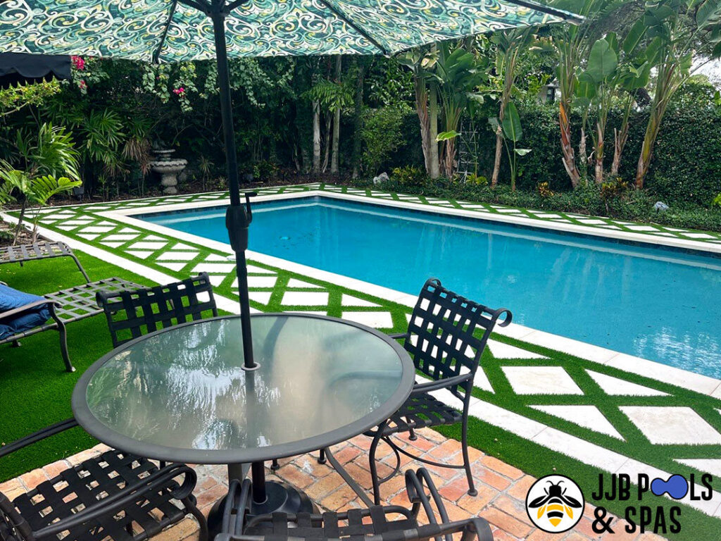 A modern rectangular pool surrounded by artificial turf and white pavers in a tropical backyard, completed by JJB Pools & Spas in Tampa, FL.