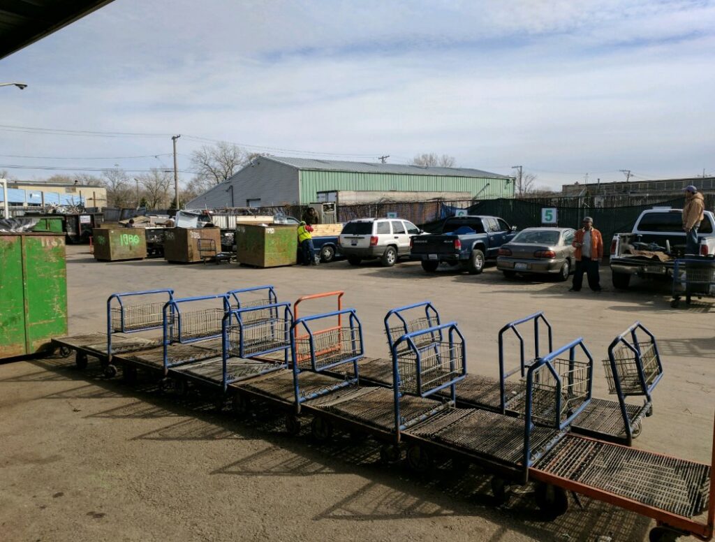 The busy outdoor yard of the recycling facility with carts and trucks at Get Green Recycling Co. in Aurora, IL.