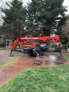 A red JLG Platform 72ft Arborist lift parked on a lawn, used by Scott Lanes Tree Service in Chesapeake, VA.