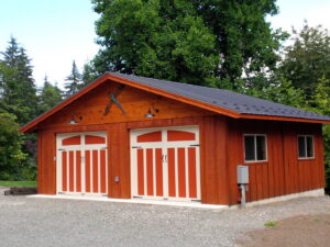 A red barn-style garage with two orange and white garage doors by Garages Etc in Tacoma, WA
