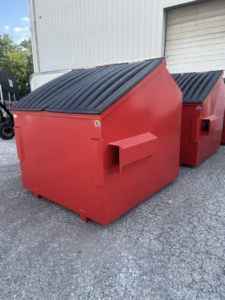 A bright red commercial dumpster with a sloped lid from Eagle Industrial Solutions in Louisville, KY.