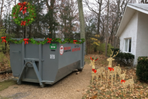 A Red Dog Dumpsters rental dumpster decorated with Christmas garland and a wreath outside a home in Nashville, TN