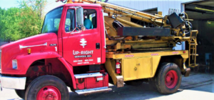 A red truck equipped with a drilling and augering rig for Upright Services Inc in Green Bay, WI.
