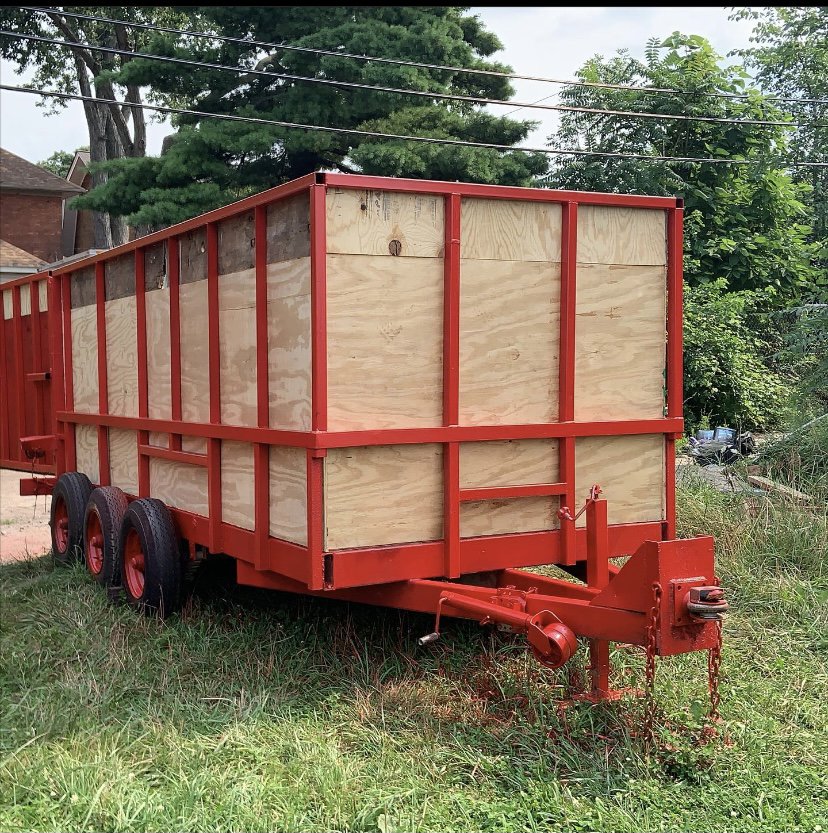 A red dump trailer with wooden side extensions from The Dump Town, ready for junk removal in Detroit, MI.