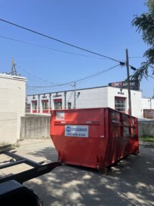 A red dumpster from 515 Dumpsters being delivered to a commercial building in West Des Moines, IA.