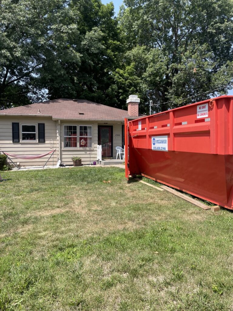 A red dumpster from 515 Dumpsters placed in front of a residential house in West Des Moines, IA.
