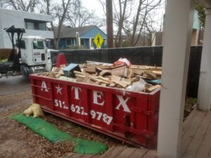 A red roll-off dumpster filled with wood and general debris by ATEX Dumpsters Services in Austin, TX.