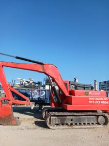 A red excavator with the FL Scrap logo and contact information, used for general junk removal services in El Paso, TX.