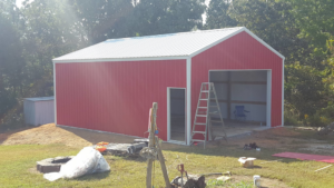 A red metal garage with a white roof and an open bay, showing construction in progress by D.H. Construction in Jackson, TN.