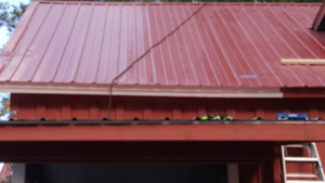 New gutter installation on a red metal roof by Handyman Heroes, offering reliable roofing services in Roswell, NM.