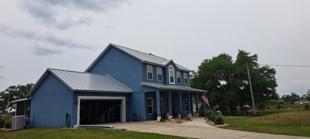 A residential home featuring a vibrant red metal roof and a backyard pool area, completed by Hastings Roofing Service Inc. in Orlando, FL.