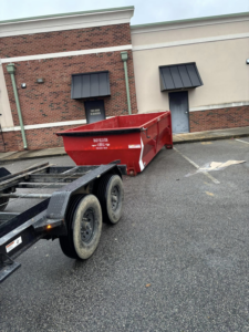 A red roll-off dumpster being delivered for commercial junk removal by BRR services in Fayetteville, NC
