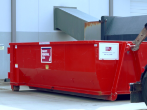 A red roll-off dumpster placed on the ground by Waste Removal USA for general junk removal services in Austin, TX