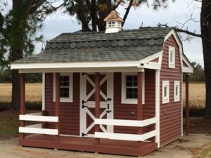 A charming red shed with a small front porch and white railing, built by RMG Construction in Chesapeake, VA.