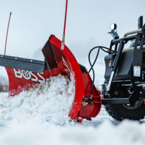 A red snowplow attached to a vehicle clearing snow, available from Handyman Rental in Portland, ME.