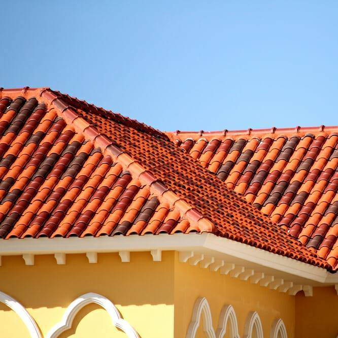 A vibrant red tile roof on a yellow building, showcasing quality craftsmanship by Florida Roof & Building Services LLC in Ellenton, FL.