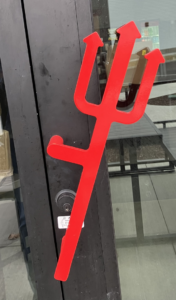 A red trident-shaped door handle installed on a black commercial door by KPS Commercial Construction in Arcadia, IN.