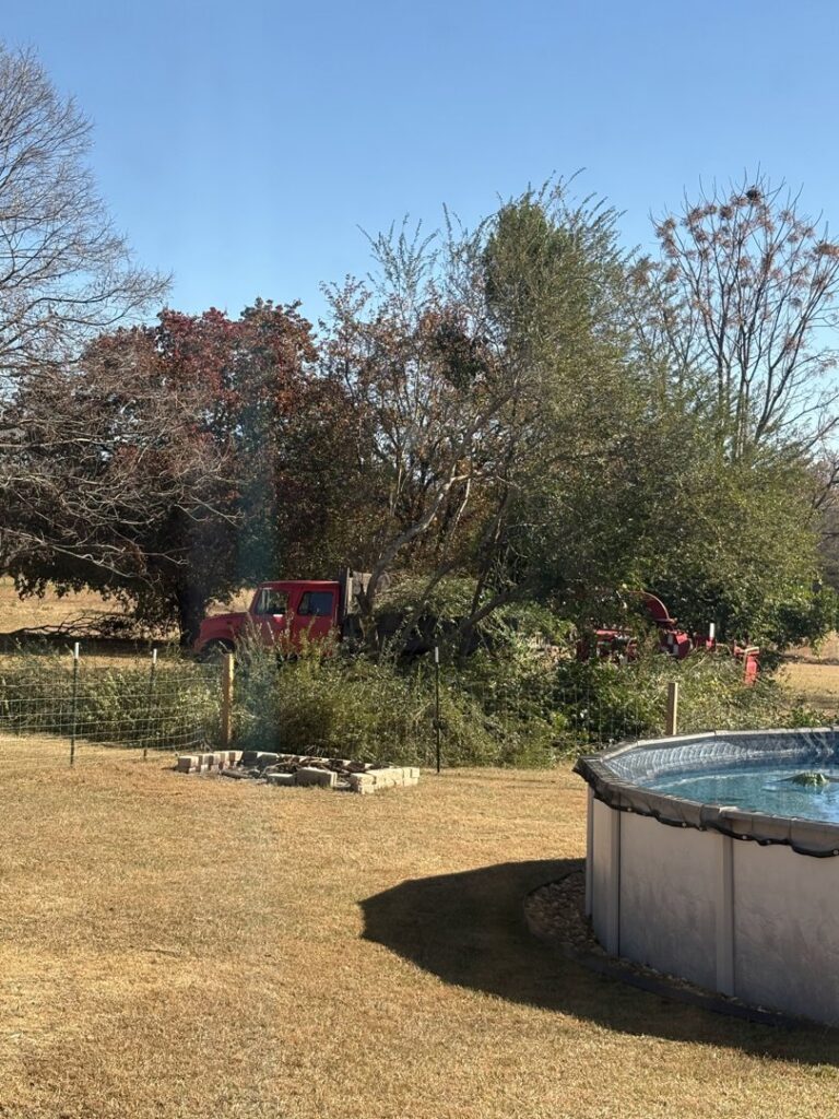 A red truck and wood chipper surrounded by tree debris, indicating cleanup after tree service work by Knotty Branches Tree Service in Macon, GA.