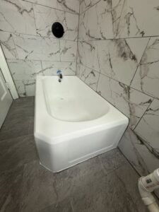 A completed bathroom with a refinished tub and elegant marble-look wall tiles by Phillys Finest Tub & Tile Refinishing in Philadelphia, PA