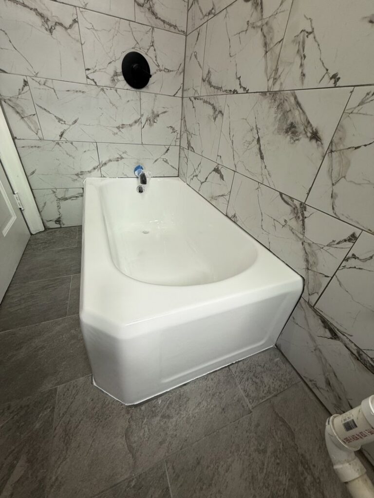 A completed bathroom with a refinished tub and elegant marble-look wall tiles by Phillys Finest Tub & Tile Refinishing in Philadelphia, PA
