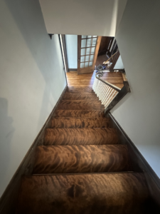 A beautifully refinished wood floor visible at the bottom of a staircase by SANDMAN WOOD FLOOR REFINISHING in Cleveland, OH.