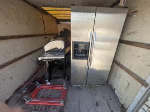 A large stainless steel refrigerator and grill loaded inside a Haul Squad junk removal truck in Helena, AL.