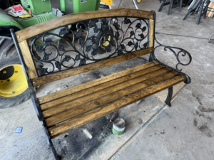 A beautifully refurbished outdoor bench with wooden slats and wrought iron details by Bill's Handyman Services in Anchorage, AK.