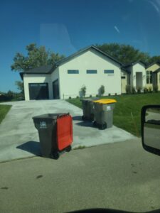 A Husker Refuse Services truck driving on a residential street in Lincoln, NE, providing junk removal.
