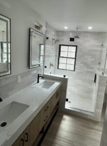 A newly remodeled bathroom featuring a double vanity, modern mirrors, and a spacious walk-in shower by Impressive Basements in Westland, MI.