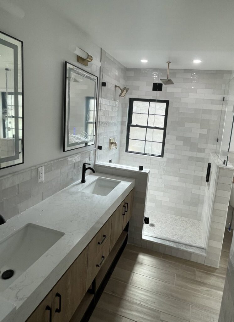 A newly remodeled bathroom featuring a double vanity, modern mirrors, and a spacious walk-in shower by Impressive Basements in Westland, MI.