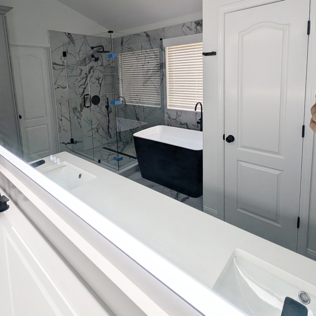 A beautifully remodeled bathroom featuring a double vanity, glass shower, and freestanding tub by Ensotile - Atlanta Bathroom Remodeling in Stone Mountain, GA