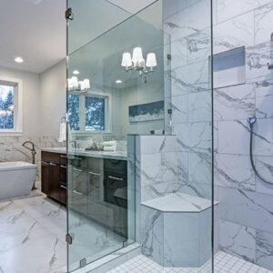 A beautifully remodeled bathroom featuring a spacious glass shower and marble-look tiles by Creative Building & Remodeling in Warren, MI