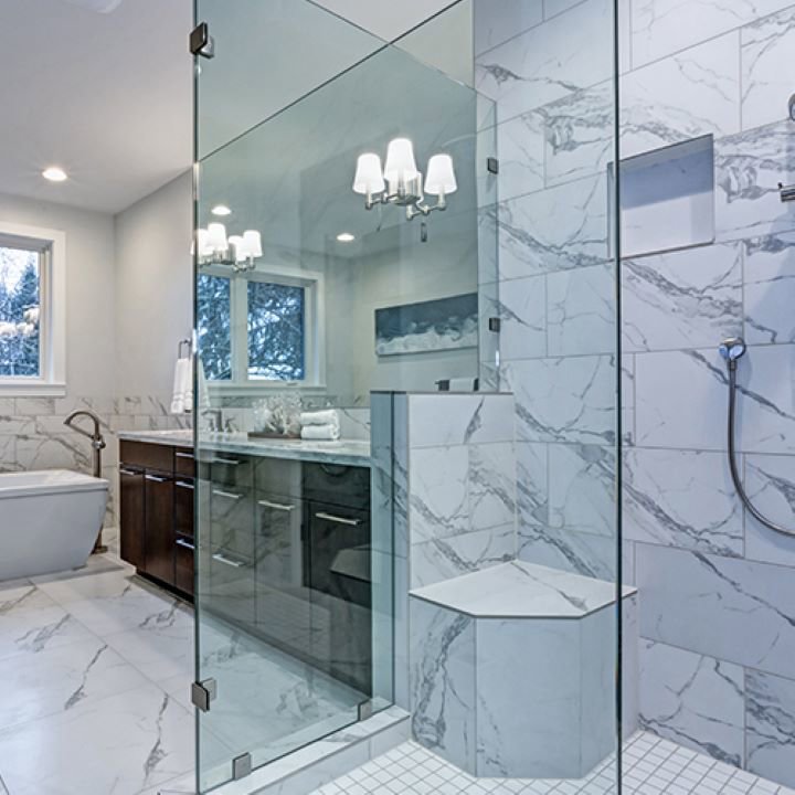 A beautifully remodeled bathroom featuring a spacious glass shower and marble-look tiles by Creative Building & Remodeling in Warren, MI