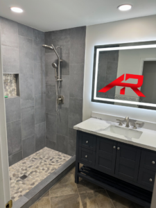 A newly remodeled bathroom featuring a walk-in shower with pebble floor and a modern vanity with an LED mirror by AGM Remodeling LLC in Glendale, AZ.