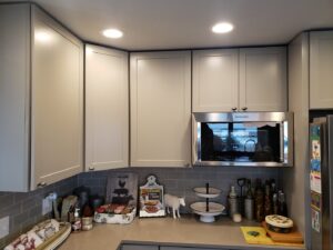 A newly remodeled kitchen featuring new cabinets, microwave, and recessed lighting by Rosewalls Handyman & Remodeling in Des Moines, IA.