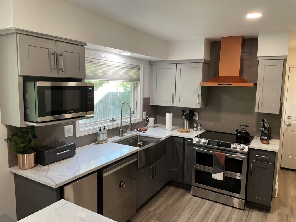 A modern remodeled kitchen featuring grey and white cabinets with sleek white countertops by Impressive Basements in Westland, MI.