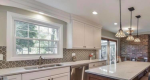 A beautifully remodeled kitchen featuring white cabinets, a patterned backsplash, and a large island by FAV Remodeling Services LLC in Gurnee, IL.