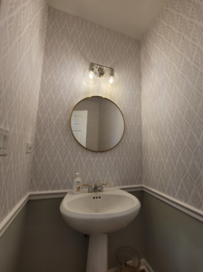A stylish remodeled powder room featuring a pedestal sink, modern light fixture, and patterned wallpaper by FAV Remodeling Services LLC in Gurnee, IL.
