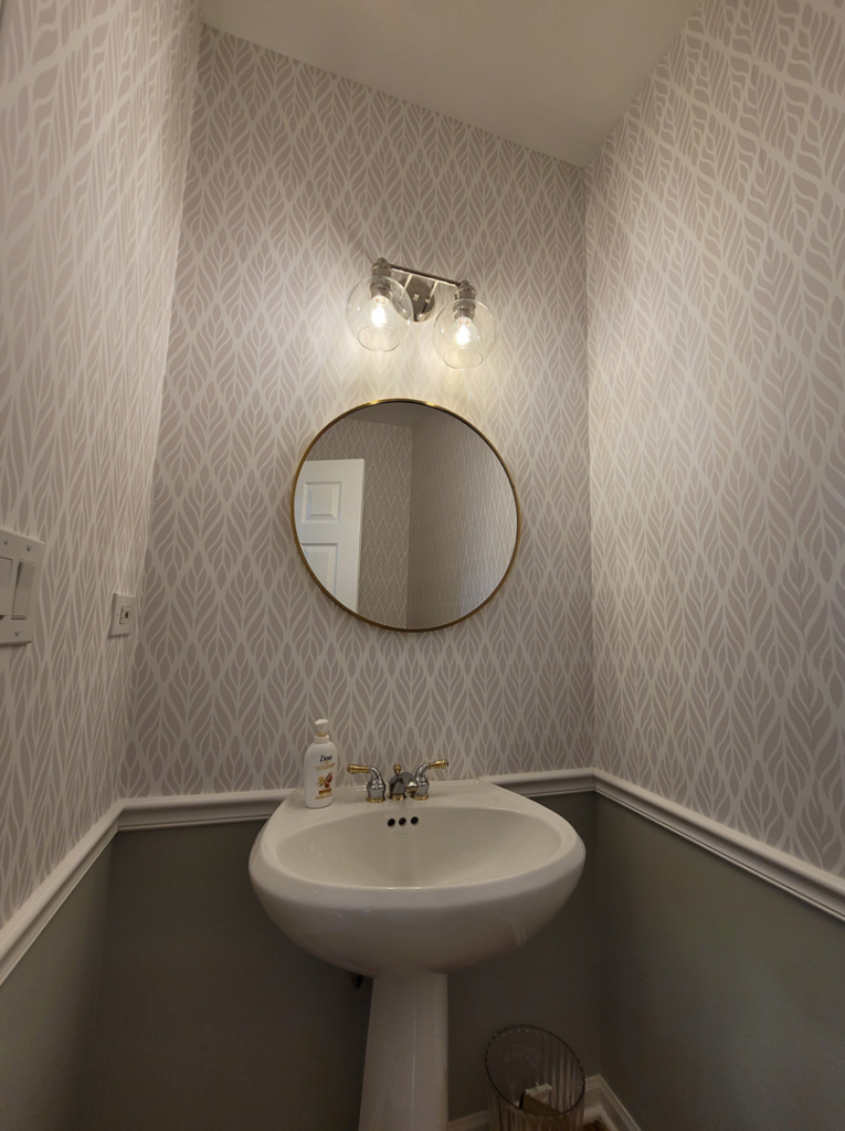 A stylish remodeled powder room featuring a pedestal sink, modern light fixture, and patterned wallpaper by FAV Remodeling Services LLC in Gurnee, IL.