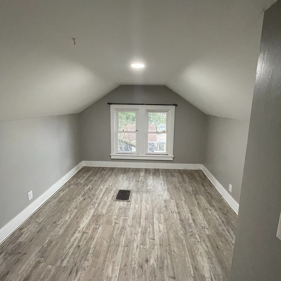 A newly renovated attic room with light gray walls and new laminate flooring by Chris Pierce Construction in Sioux City, IA.