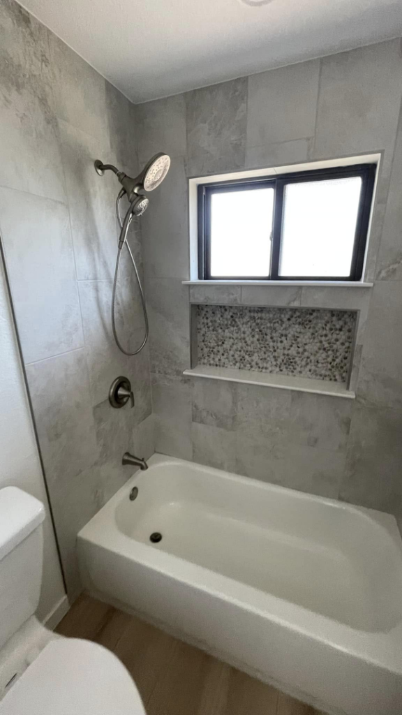 A renovated bathroom featuring a clean bathtub, tiled walls, and a window, completed by D.R. Construction in El Paso, TX.