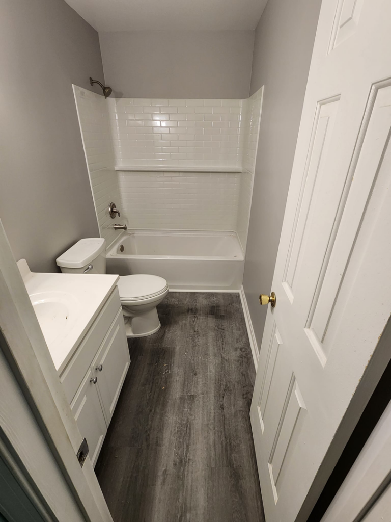 A newly renovated bathroom with a white vanity, toilet, and subway tile shower completed by Lehr Design Build LLC in Salisbury, MD.