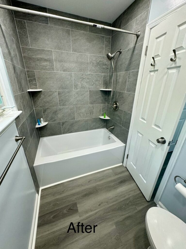 A newly renovated bathroom featuring a white bathtub, grey tiled walls, and modern flooring by RepairTo Roofing, Renovations & Repairs in Wilmington, DE.