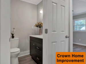 A renovated bathroom with a new vanity, sink, toilet, and modern light fixture installed by Crown Home Improvements in Charlotte, NC