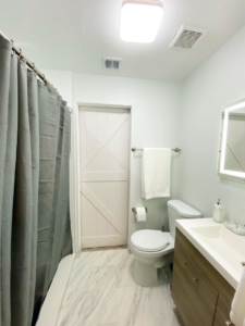 A renovated bathroom featuring a shower, toilet, and barn-style door by Property Solutions Network, Llc in Hialeah, FL