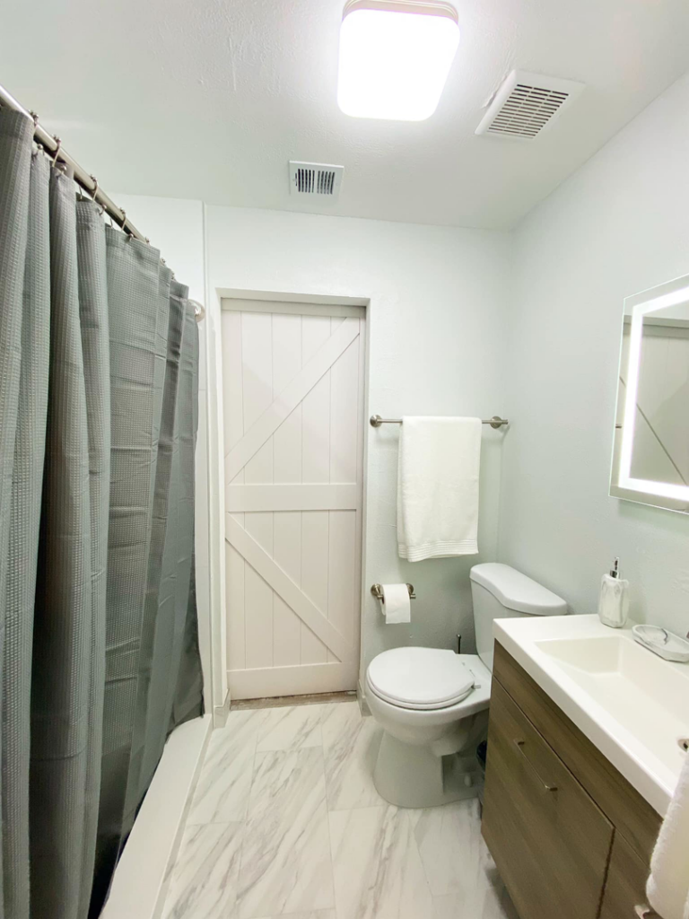 A renovated bathroom featuring a shower, toilet, and barn-style door by Property Solutions Network, Llc in Hialeah, FL