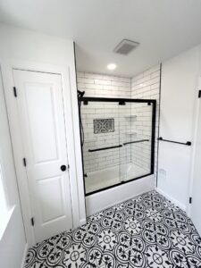 A renovated bathroom featuring a shower/tub combo with subway tiles and a distinctive patterned floor by RW Contracting Phila, LLC in Philadelphia, PA.