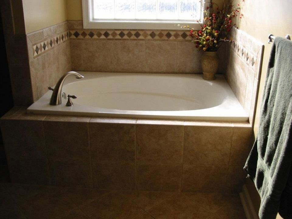 A renovated bathroom showcasing a tiled bathtub and surrounding area, completed by WHE Construction in Virginia Beach, VA
