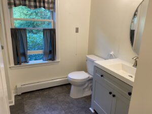 A newly renovated bathroom featuring a white toilet, modern vanity, and window by Coastal Home Improvements in Greenwood, DE.