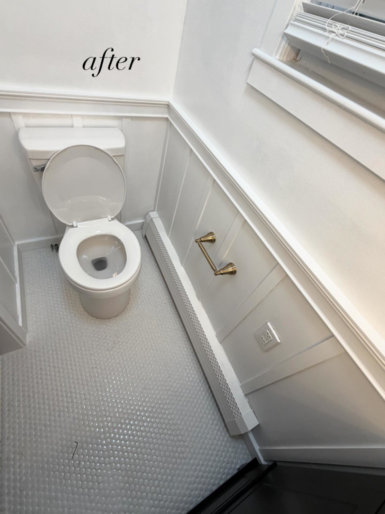 A newly renovated bathroom featuring a white toilet, wainscoting, and new flooring, completed by NOAT in North Providence, RI.